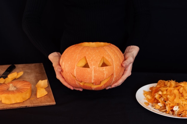 Abóbora caseira de laranja para o Halloween nas mãos de uma mulher