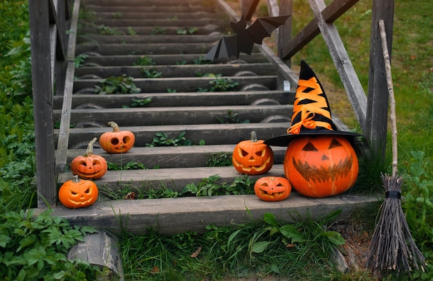 Abóbora com chapéu de bruxa nos degraus da escada em frente à casa no Halloween