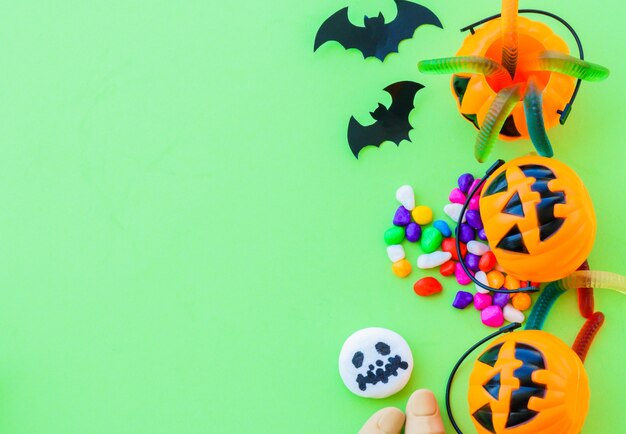 Abóbora de halloween com doces doces sobre fundo verde