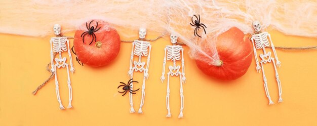 Abóbora de Halloween com esqueleto de teia de aranha e aranhas pretas em fundo laranja