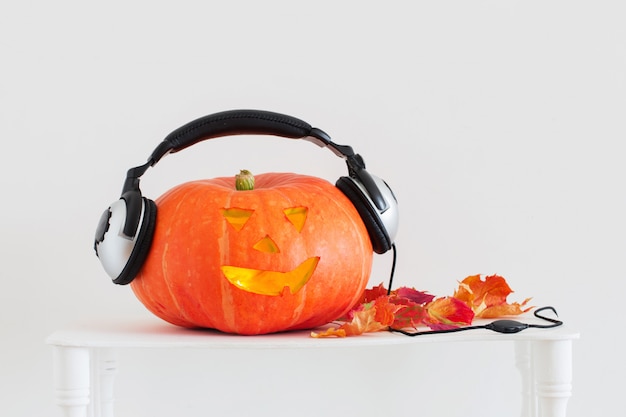 Abóbora de Halloween com fones de ouvido no fundo branco