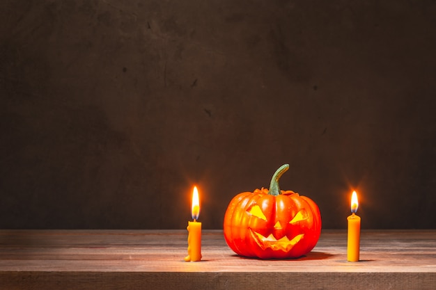 Abóbora de Halloween e velas amarelas na mesa de madeira