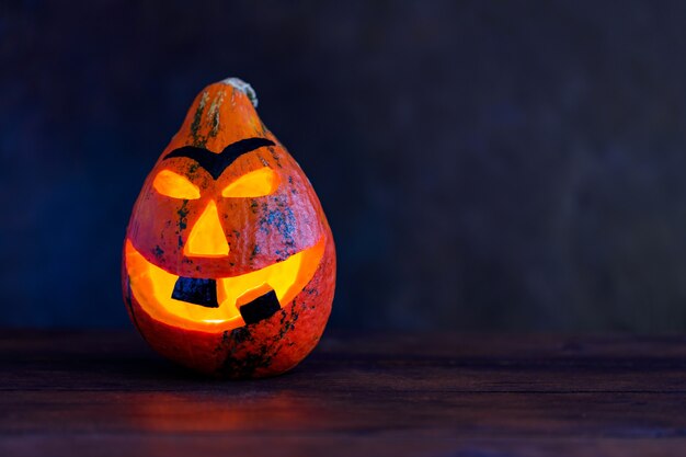 Abóbora de Halloween em um fundo escuro. Sorriso de abóbora de Halloween e olhos assustadores para a noite de festa. Copie o espaço