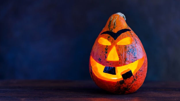 Abóbora de Halloween em um fundo escuro. Sorriso de abóbora de Halloween e olhos assustadores para a noite de festa. Copie o espaço