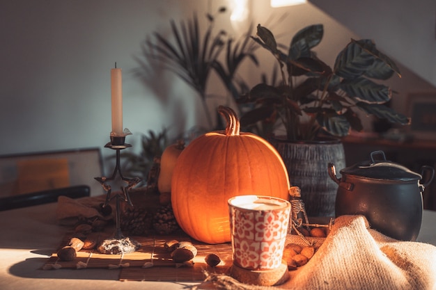 Abóbora de Halloween em uma mesa com decoração Esqueleto velas nozes