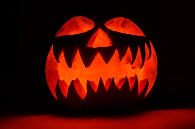 Foto abóbora de halloween luminosa assustadora em fundo preto