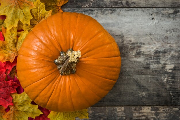 Abóbora de halloween natural com folhas de outono na mesa de madeira