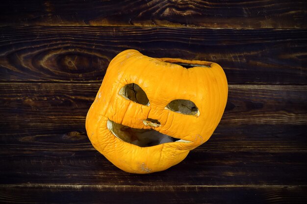 Foto abóbora de halloween obsoleta na superfície da placa de madeira jack o lantern face murcha