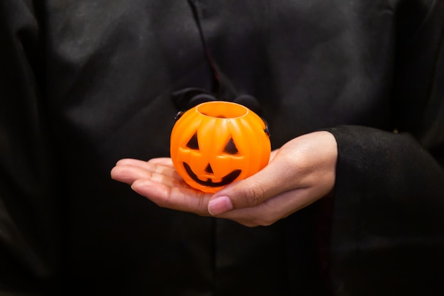 Abóbora na mão, garota vestindo traje preto na festa de Halloween