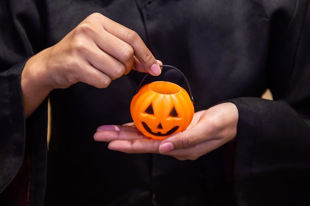 Abóbora na mão, garota vestindo traje preto na festa de Halloween