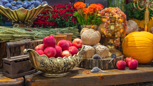 Abóboras com frutas pão legumes uvas e flores na mesa de madeira rústica