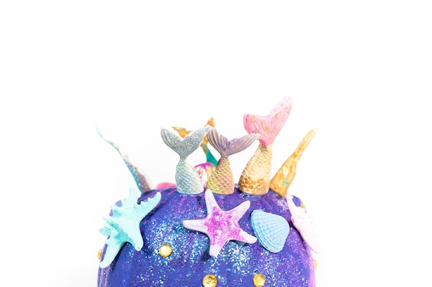 Abóboras de artesanato de Halloween decoradas com caudas de sereia, glitter e strass brilhantes em um fundo branco.