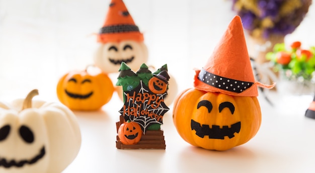 Abóboras de fantasma brancas e amarelas com chapéu de bruxa e texto de feliz dia das bruxas em borad.