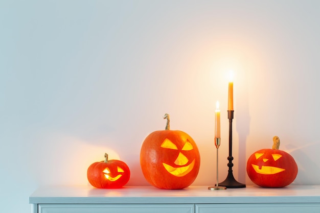 Abóboras de halloween com velas acesas no interior branco