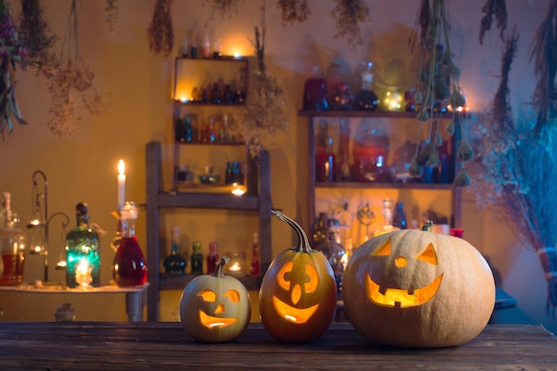 Abóboras de Halloween com velas e poções mágicas à noite dentro de casa