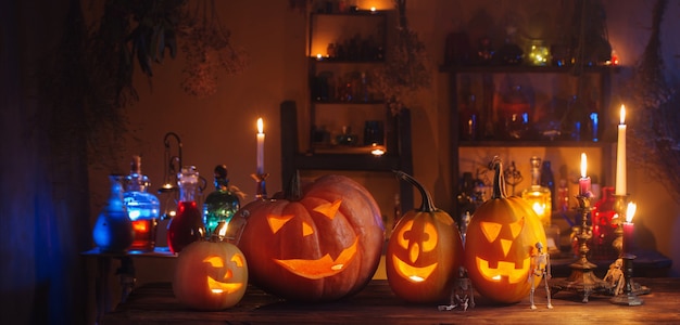 Abóboras de Halloween com velas e poções mágicas à noite dentro de casa