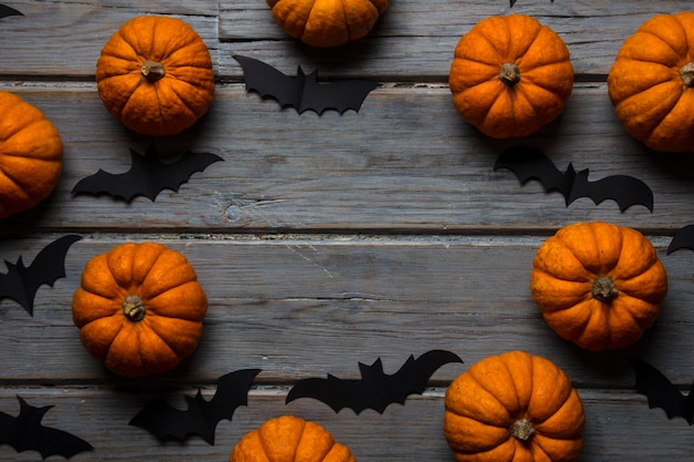 Abóboras de Halloween e morcegos vampiros pretos em um fundo de madeira