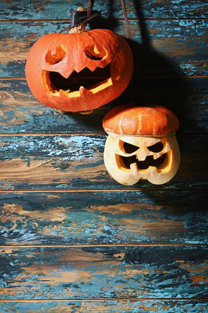 Abóboras de tamanho diferente na parede azul de madeira esculpindo uma abóbora para o Halloween