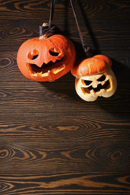 Abóboras de tamanho diferente na parede marrom de madeira esculpindo uma abóbora para o Halloween