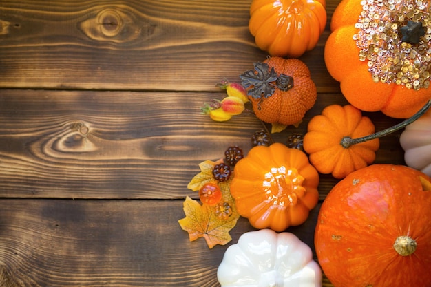 Abóboras laranja e brancas em uma mesa de madeira com maple amarelo de outono deixa bagas com copyspace Humor de outono colheita de halloween decoração de casa de ação de graças