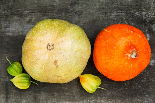 Abóboras multicoloridas e physalis em uma mesa de madeira cinza. Vitaminas e alimentação saudável. Fechar-se.