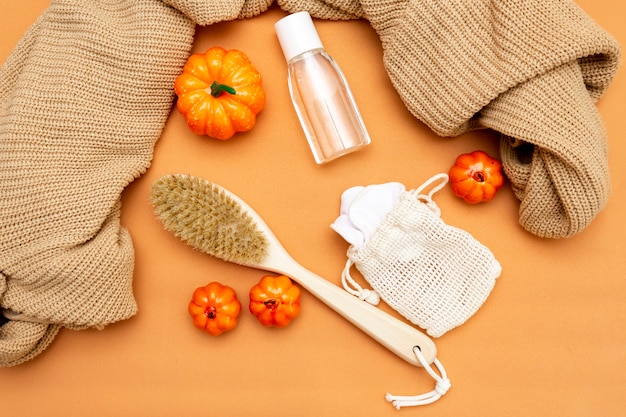 Abóboras, uma escova corporal natural, demaquilante, esponjas e um agasalho quente sobre fundo bege. Cosméticos para rosto e corpo. Layout de outono. Vista do topo