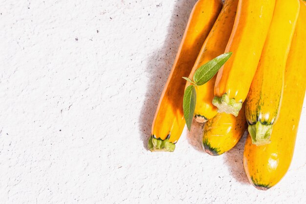 Abobrinha de laranja fresca. Colheita de vegetais maduros. Luz dura moderna, sombra escura, fundo de massa branca, vista de cima