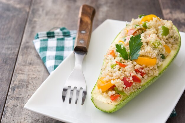 Abobrinha recheada com quinoa e legumes no espaço da cópia de mesa de madeira