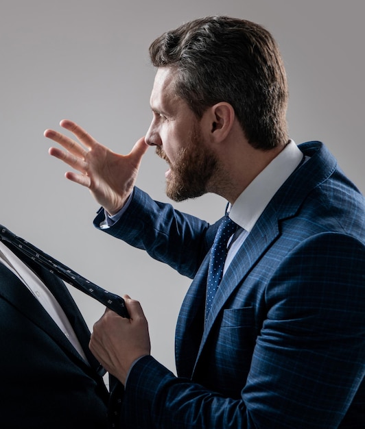 Abogado agresivo en traje que amenaza gesto tirando hombre corbata fondo gris amenazante