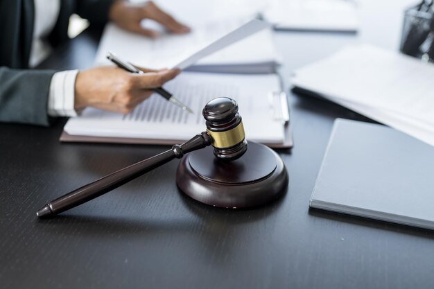 Foto abogado empresario que trabaja con el libro de leyes en la oficina o en la sala del tribunal asesor legal con martillo y derecho legal justicia y concepto de abogado juez martillo martillo en el escritorio del abogado