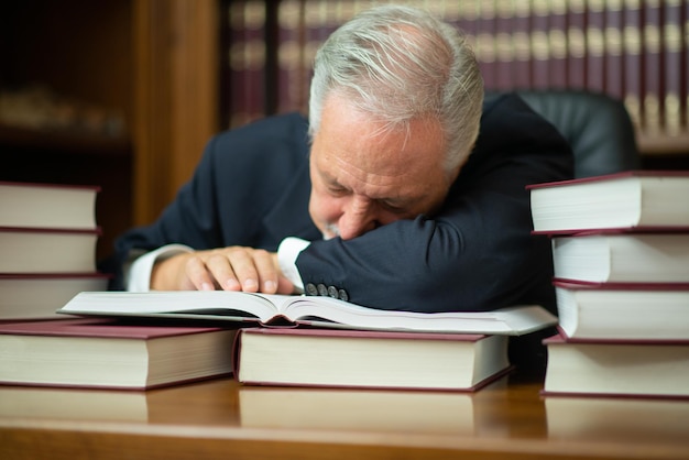Abogado empresario soñoliento rodeado de muchos libros