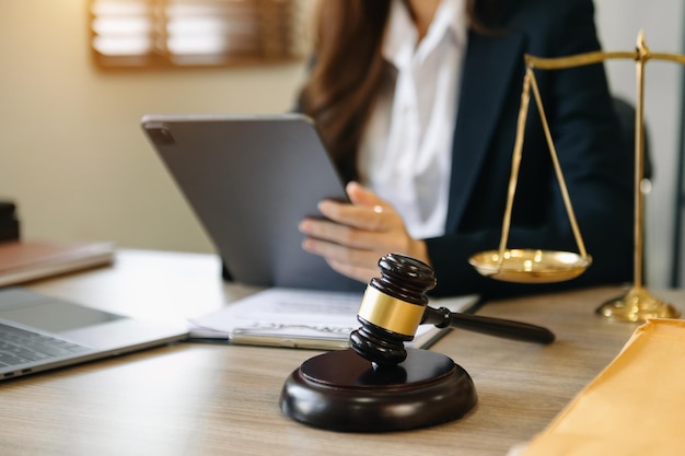 Abogado masculino en la oficina con escala de latón y usando tableta y computadora portátil en la mesa de madera concepto de justicia y derecho