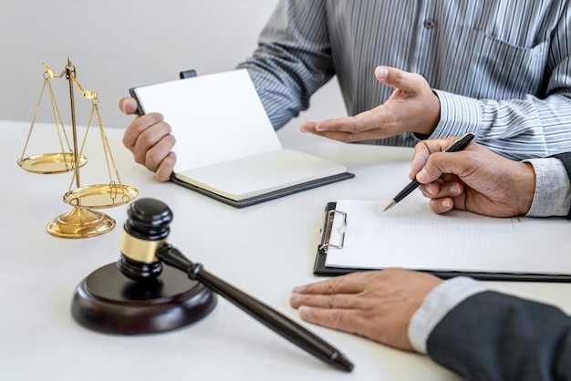 El abogado o consejero masculino que trabaja en la sala del tribunal se reúne con el cliente y consulta los documentos del contrato de bienes raíces, concepto de servicios legales y legales.