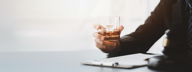 Un abogado sosteniendo un vaso de whisky Está en su oficina y está estresado por argumentar por un cliente que es abogado El concepto de litigio legal claro