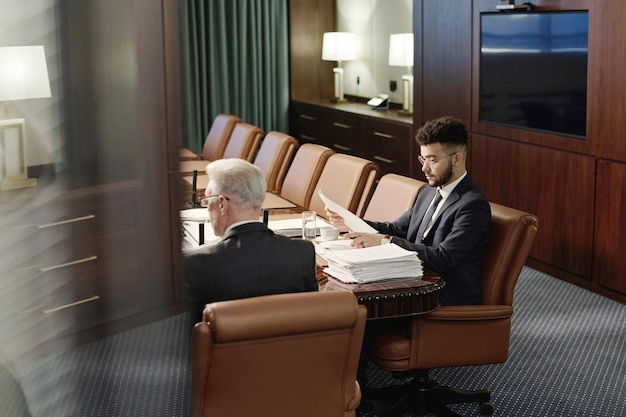 Abogados profesionales trabajando con documentos sentados uno al lado del otro en el escritorio