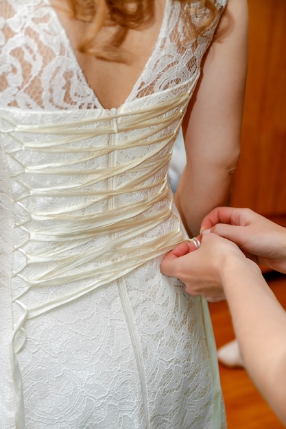 Abotoando o vestido de casamento da noiva. Fechar-se.