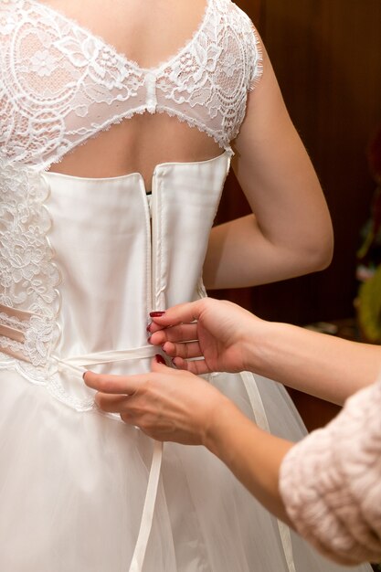 Abotoando o vestido de casamento da noiva. Fechar-se.