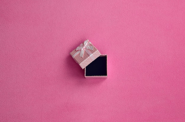 Abra a caixa de presente pequena em rosa com um pequeno arco encontra-se em um cobertor