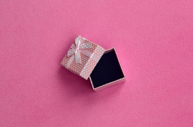 Foto abra a caixa de presente pequena em rosa com um pequeno arco encontra-se em um cobertor