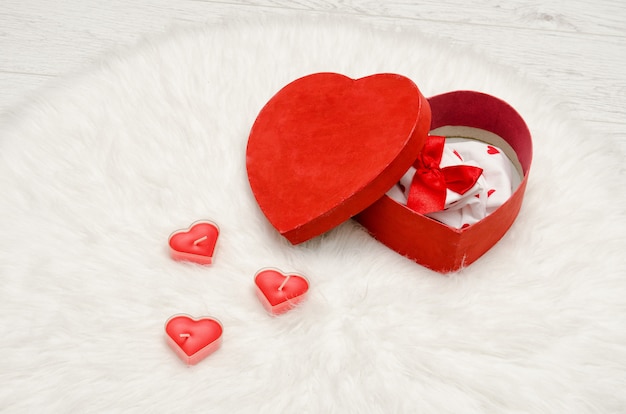 Abra a caixa vermelha com linho vermelho e branco em forma de coração com um pêlo branco. velas em forma de coração