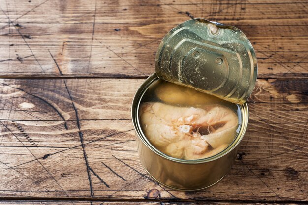 Abra a lata de lata com peixe salmão rosa sobre fundo de madeira.