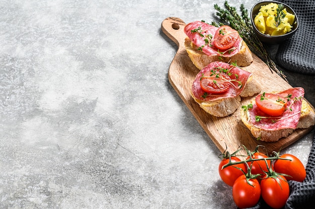 Abra el bocadillo de baguette con salchichón de salami, tomates cherry y microgreens. vista superior. Copia espacio