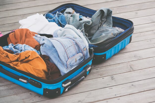 Abra la bolsa de viaje con ropa, accesorios en el piso de madera.