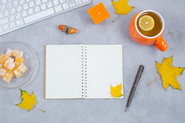 Abra el calendario del cuaderno diario en blanco con hojas amarillas y dulces de velas de té y teclado