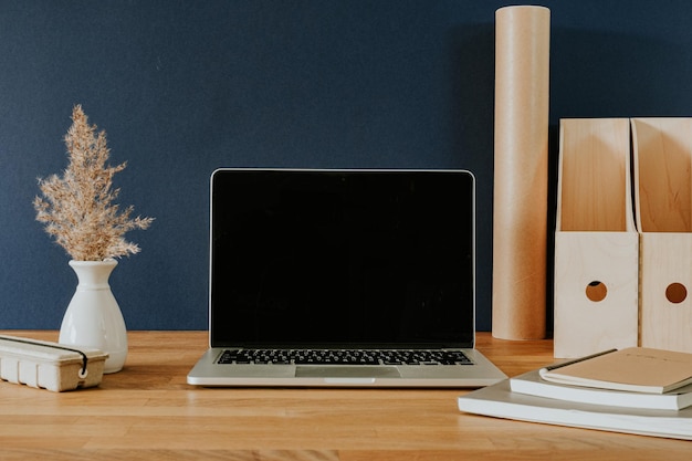 Abra la computadora portátil y los artículos de papelería en la mesa de madera