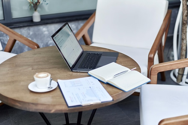 Abra el cuaderno y una computadora portátil en la mesa en un cibercafé