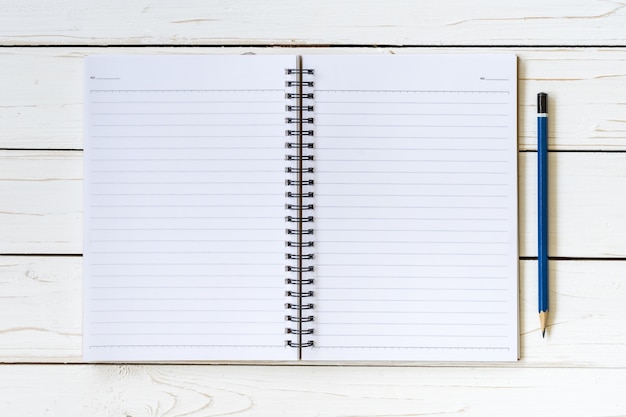 Abra el cuaderno con las páginas en blanco y el lápiz en la mesa de madera