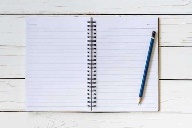 Abra el cuaderno con las páginas en blanco y el lápiz en la mesa de madera