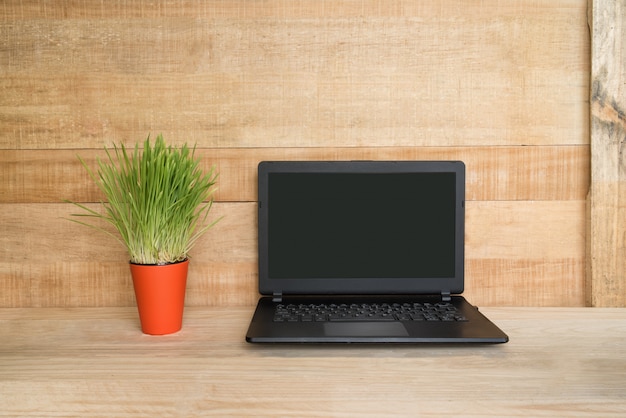 Abra el cuaderno y la planta de interior verde sobre la mesa. Lugar de trabajo a domicilio. Espacio de madera.