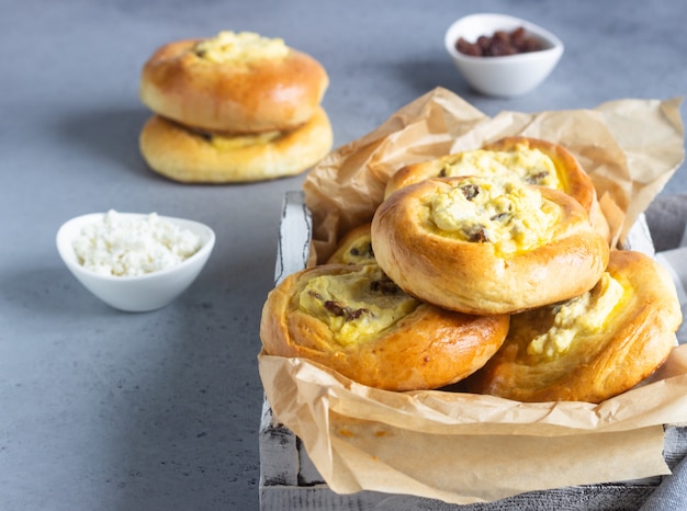 Abra las empanadas (bollos) con requesón y pasas.